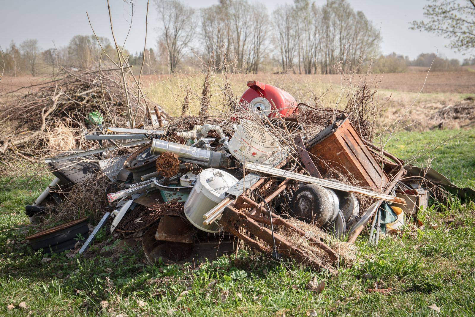 Pile of scrap metal, old appliances, and brush on a rural property in Mechanicsville, MD